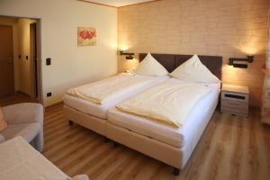 ein Schlafzimmer mit einem großen Bett mit weißer Bettwäsche und Kissen in der Unterkunft Hotel Haus Christa in Bad Bertrich