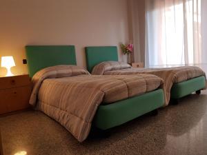 a bedroom with two beds with green headboards at Appartamenti Rho Fiera in Pero