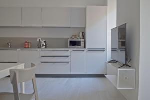 a white kitchen with white cabinets and a tv at Casa Bacca apartments in Trento