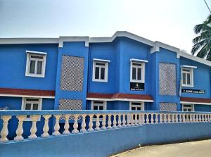 a blue building with a fence in front of it at Bijou Guest House in Baga