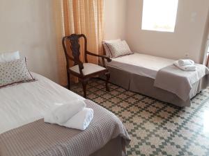 a bedroom with two beds and a chair and a window at MARIA GUESTHOUSE KINI in Kinion