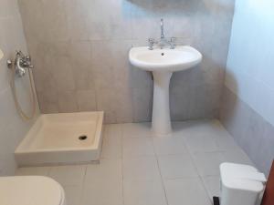 a white bathroom with a sink and a toilet at MARIA GUESTHOUSE KINI in Kinion