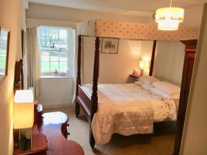 a bedroom with a canopy bed and a window at The Falcon Inn in Arncliffe