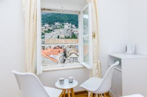 a room with a window and white chairs and a table at Cinema View House in Dubrovnik