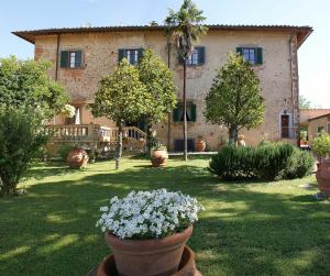 un bâtiment avec une cour fleurie devant elle dans l'établissement Villa Il Fedino, à San Casciano in Val di Pesa