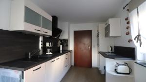 a kitchen with white cabinets and black counter tops at Ferienhaus Steinbach in Oberasbach