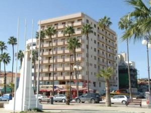 un grand bâtiment avec des palmiers devant lui dans l'établissement Ithaki Phinikoudes Apartment No. 201, à Larnaka