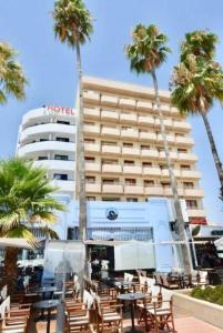 a hotel with chairs and palm trees in front of it at Ithaki Phinikoudes Apartment No. 105 in Larnaka