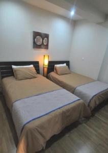 duas camas num quarto com duas lâmpadas em Ithaki Phinikoudes Apartment No. 105 em Lárnaca