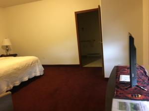 1 dormitorio con 1 cama y TV en una mesa en Greenwood Village Inn & Suites, en Kalispell