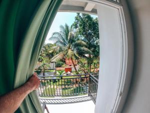 a man looking out a window at a palm tree at Green Hill Mirissa in Mirissa
