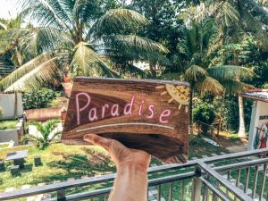 a person holding up a wooden sign that reads paradise at Green Hill Mirissa in Mirissa