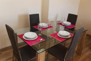 a glass table with chairs and plates and wine glasses at Apartamento Turistico Puente Romano P4 bajo C in Salamanca