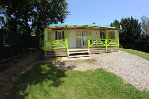 un petit hangar avec un toit vert sur l'herbe dans l'établissement Parc Des Oliviers, à Gaudiès