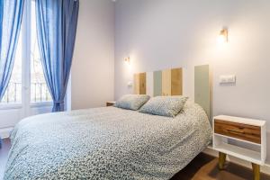 a bedroom with a bed with blue curtains and a window at La Latina XII in Madrid