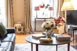 una sala de estar con una mesa con libros y un jarrón de flores en GRAND & SPACIOUS CENTRAL APT WITH WiFi, en Edimburgo