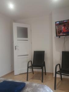 ein Wohnzimmer mit 2 Stühlen und einem TV an der Wand in der Unterkunft ZELWAGI 14 in Mikołajki