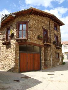 a stone house with a wooden door and a balcony at La Badila in Garganta de los Montes