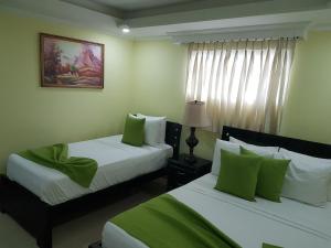 Habitación de hotel con 2 camas con almohadas verdes en Hotel Sol Del Este en Cartagena de Indias