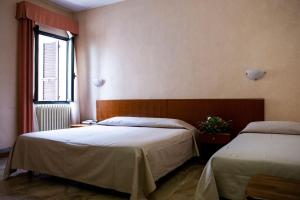 een slaapkamer met 2 bedden en een raam bij Hotel Astor in Piacenza