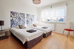 sypialnia z 2 łóżkami i krzesłem w obiekcie Les Appartements Saint-Michel - centre-ville 2 chambres 90m2 avec garage w mieście Saint-Brieuc