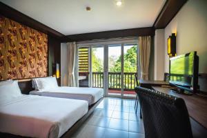 a hotel room with two beds and a television at Ratana Hotel Chalong in Rawai Beach