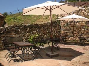 two tables and chairs with an umbrella in front of a stone wall at Hotel Rural Genestoso in Genestoso