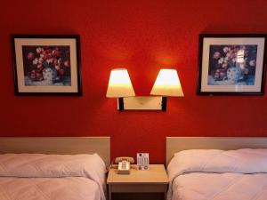 a red room with two beds and a phone on a table at QC Stay Inn in Moline
