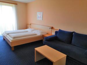 une chambre d'hôtel avec un lit et un canapé dans l'établissement Kunstcafe Rooms, à Stegersbach