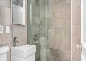 a bathroom with a shower with a sink and a toilet at Bay Village Suites in Boston