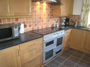 a kitchen with a stove and a microwave at Arden Hill Farmhouse - Hot Tub, Snooker Table, Sleeps 16 in Stratford-upon-Avon