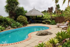 a swimming pool in a garden with a gazebo at The Yurt Wai Rua in Whangarei