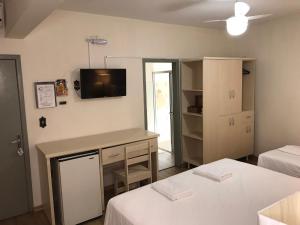 een kamer met 2 bedden en een bureau met een tv aan de muur bij Hotel Mirante in Barra Velha