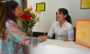 two women shaking hands at a counter with flowers at Hotel Dikran in Los Ángeles