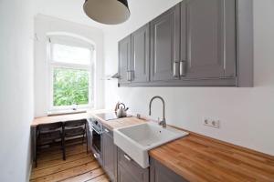 cocina con armarios grises, fregadero y ventana en Magnificent turn of century flat (legal) en Berlín