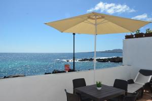 a table with an umbrella and the ocean at Casa de la playa in Punta de Mujeres