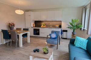 a kitchen and living room with a blue couch and a table at De Nagtegaal in Hollum