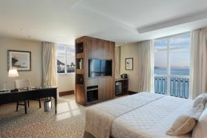 a bedroom with a bed and a desk and a television at Miramar By Windsor Copacabana in Rio de Janeiro