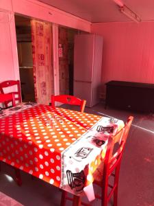 Parc Des Oliviers في Gaudiès: طاولة حمراء وبيضاء مع كراسي وثلاجة