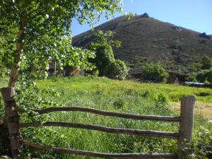 a wooden fence in a field with a hill at Hotel Rural Genestoso in Genestoso