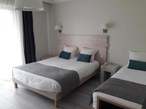 a hotel room with two beds with blue pillows at Hôtel Ker-Noyal Quiberon Plage in Quiberon