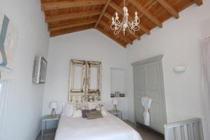 a bedroom with a white bed and a chandelier at 1901 Hermoupolis in Ermoupoli