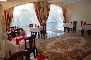 a dining room with white tables and chairs and windows at Vila Muntenia Hotel in Chişinău
