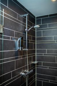 a shower in a bathroom with black tiles at Royal Amsterdam Hotel in Amsterdam