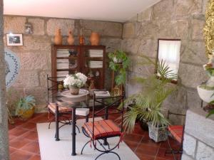 Habitación con mesa, sillas y pared de piedra. en Casa da Reina, en Viana do Castelo