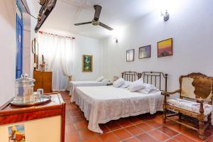 a bedroom with two beds and a chair at Hotel Casa de Las Palmas in Cartagena de Indias