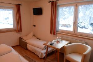 a room with a table and a couch and two windows at Blick zum Wasserfall in Sankt Leonhard im Pitztal