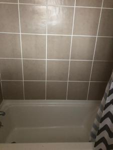 a bathroom with a tub and a tiled wall at Beachway Motel in Salisbury