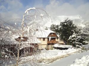 une maison recouverte de neige devant dans l'établissement Arelauquen Bungalows & Suites, à San Carlos de Bariloche