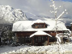 a log cabin with snow on the roof at Arelauquen Bungalows & Suites in San Carlos de Bariloche